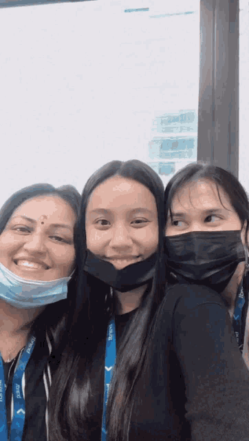 three women wearing face masks and a lanyard that says ' singapore ' on it