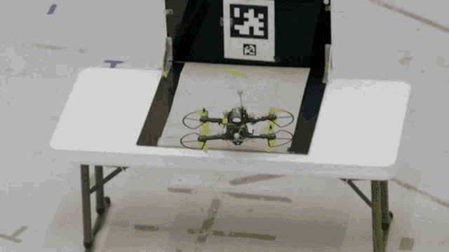 a small drone is sitting on a table in front of a sign that has the letter t on it