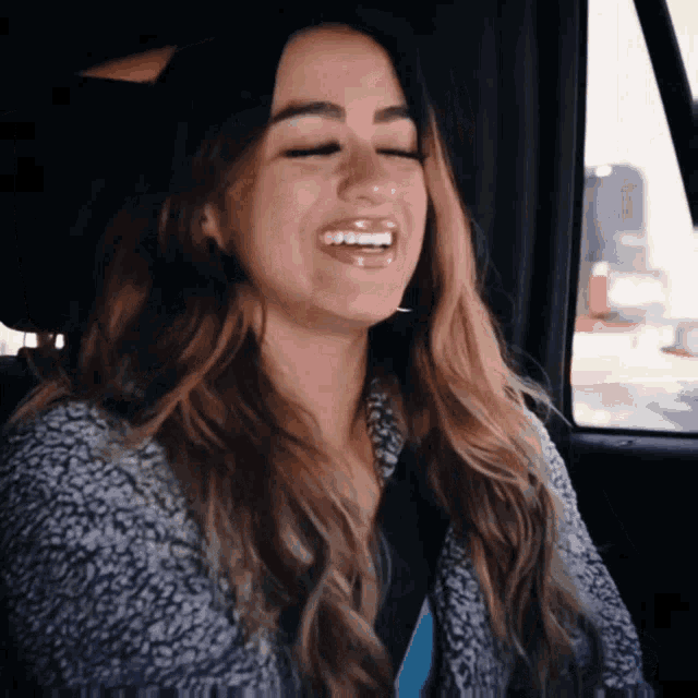 a woman in a car with her eyes closed is smiling
