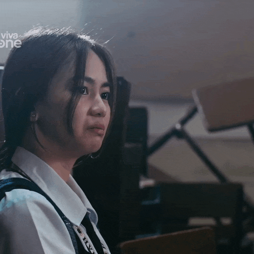 a girl sitting in a classroom with the word viva one on the bottom right
