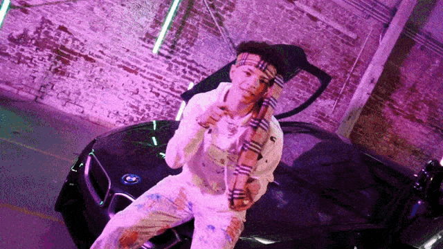 a man wearing a scarf is sitting on the back of a car