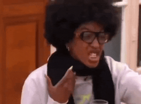 a woman with an afro and glasses is making a funny face while holding a drink .