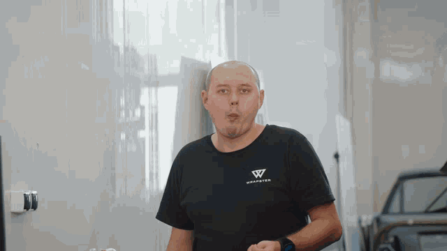 a bald man wearing a black shirt with the letter w on the front