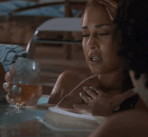 a woman sitting in a bathtub holding a glass of wine
