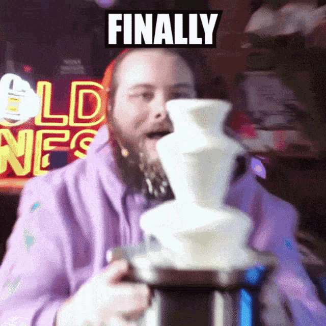 a man in a purple hoodie is eating a chocolate fountain with the words finally above him