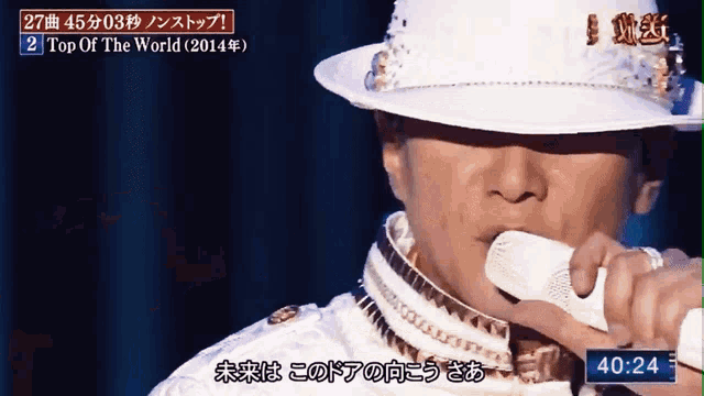 a man wearing a white hat is singing top of the world