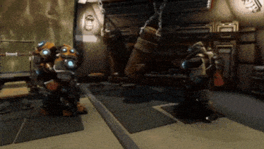two robots are standing in a room with chains hanging from the ceiling .