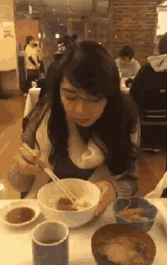 a woman is eating food with chopsticks in a restaurant .