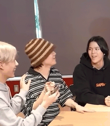 three people are sitting at a table talking to each other .