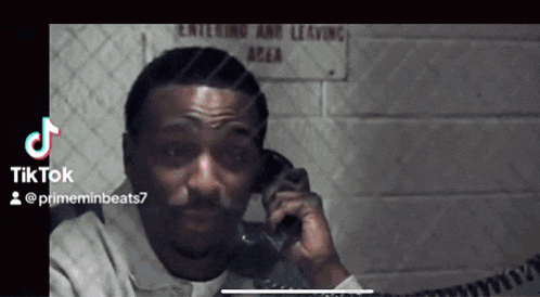 a man is talking on a phone in front of a sign that says " entering and leaving area "