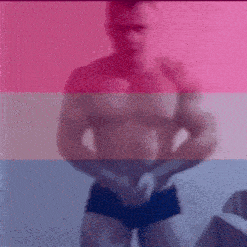 a shirtless man in shorts is standing in front of a pink , white and blue flag .