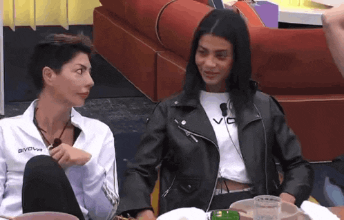 a woman wearing a givova jacket sits next to another woman wearing a white shirt