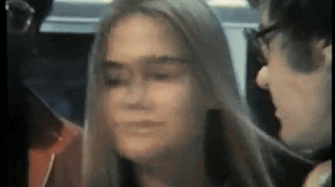 a man and a woman are sitting next to each other on a bus and looking at each other .