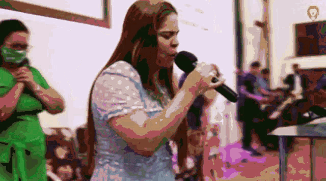a woman singing into a microphone with a mask on