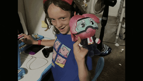 a girl in a kirby shirt is holding a stuffed animal