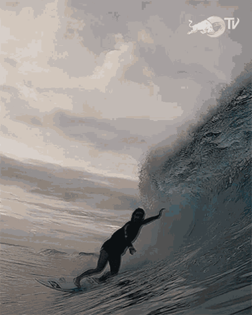 a surfer is riding a wave with a bull tv logo on the bottom