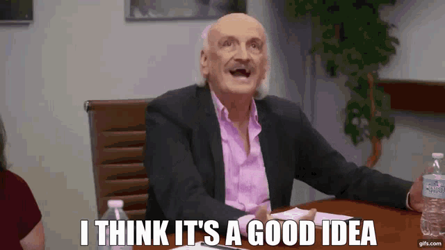 a man in a suit and pink shirt is sitting at a table and says i think it 's a good idea