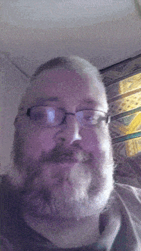 a man with a beard wearing glasses and a black shirt