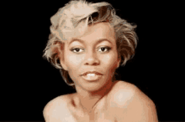 a woman without a shirt is looking at the camera with a black background
