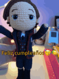 a crocheted doll says feliz cumpleanos on the bottom
