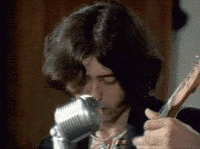 a man is singing into a microphone while playing a guitar