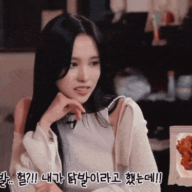 a woman with long black hair is sitting in front of a plate of food with foreign writing on it