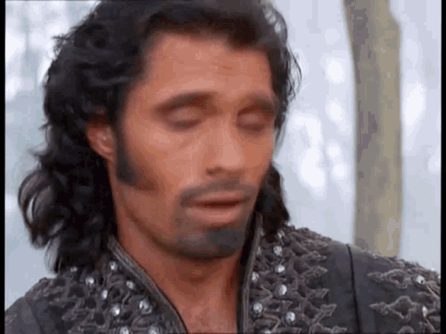 a man with long hair and a beard is making a face .