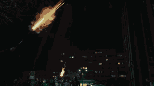 a green fireworks display is being displayed in the night sky over a city .