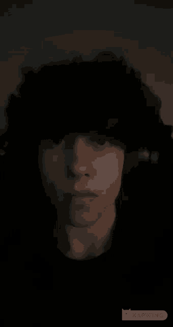 a close up of a person 's face in the dark with a black background .