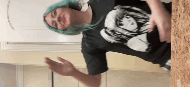 a woman with blue hair is wearing a black t-shirt with a girl on it