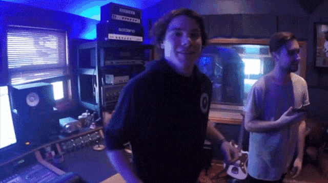 a man in a black shirt with the number 0 on it is standing in a recording studio