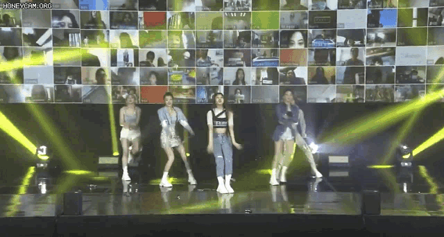 a group of young women are dancing on a stage in front of a large screen .