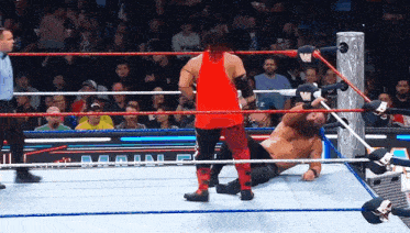 a wrestler in a red tank top is in the middle of a match