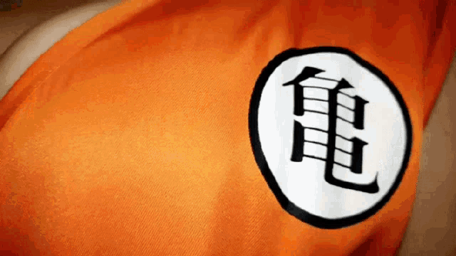 a close up of an orange shirt with a black and white symbol on it