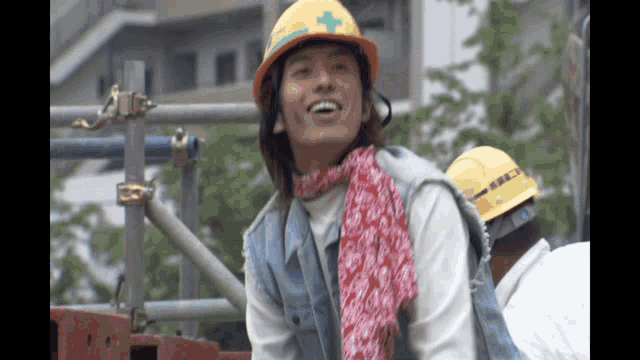 a man wearing a hard hat with a green cross on it smiles