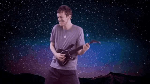 a man is holding a guitar in front of a starry sky .