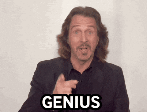 a man with long hair and a beard points at the word genius