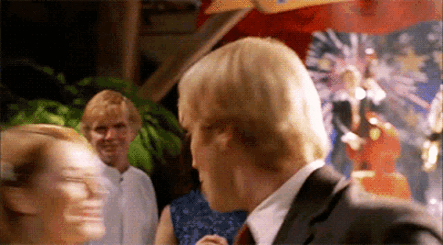 a man in a suit talks to a woman in a blue dress