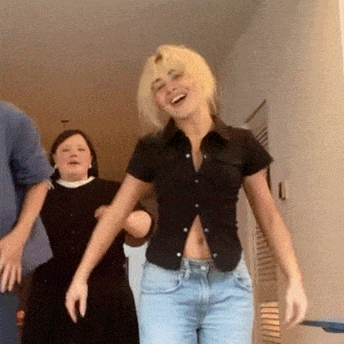 a woman in a black shirt and blue jeans is laughing while dancing