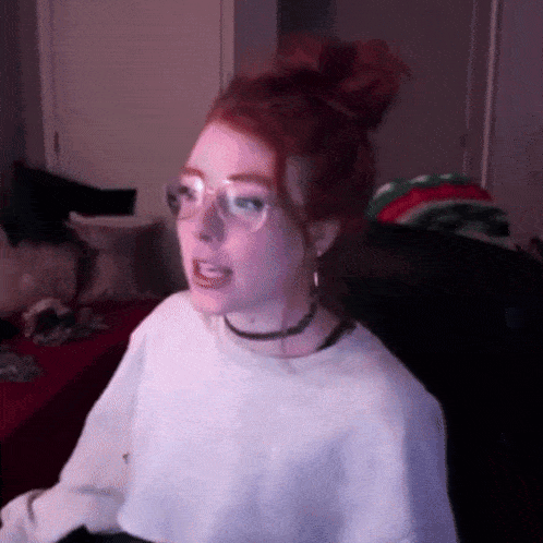 a girl with red hair is wearing glasses and a choker .