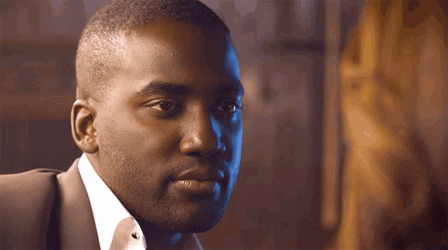 a man in a suit and tie is looking at another man