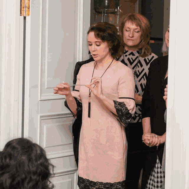 a woman in a pink dress with black lace sleeves is holding a piece of paper