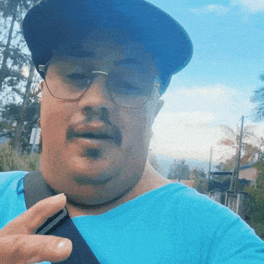 a man wearing glasses and a hat is pointing