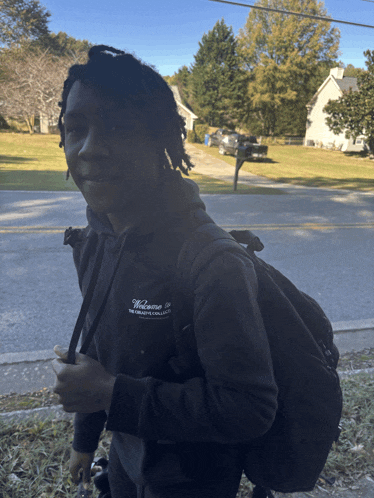 a young man wearing a black sweatshirt that says welcome to the greatest college in the world