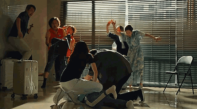 a group of people are dancing in a room with a white suitcase in the background