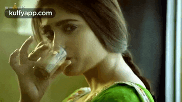 a woman is drinking a glass of milk from a glass .