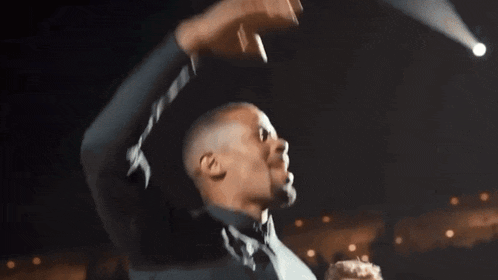 a man wearing a fruit loops sweatshirt holds his hand up in the air