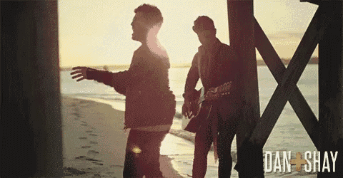 two men standing on a beach with dan and shay written in the corner
