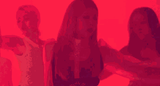 a group of women are dancing together in a red room .