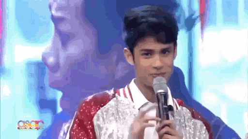 a young man is holding a microphone and smiling